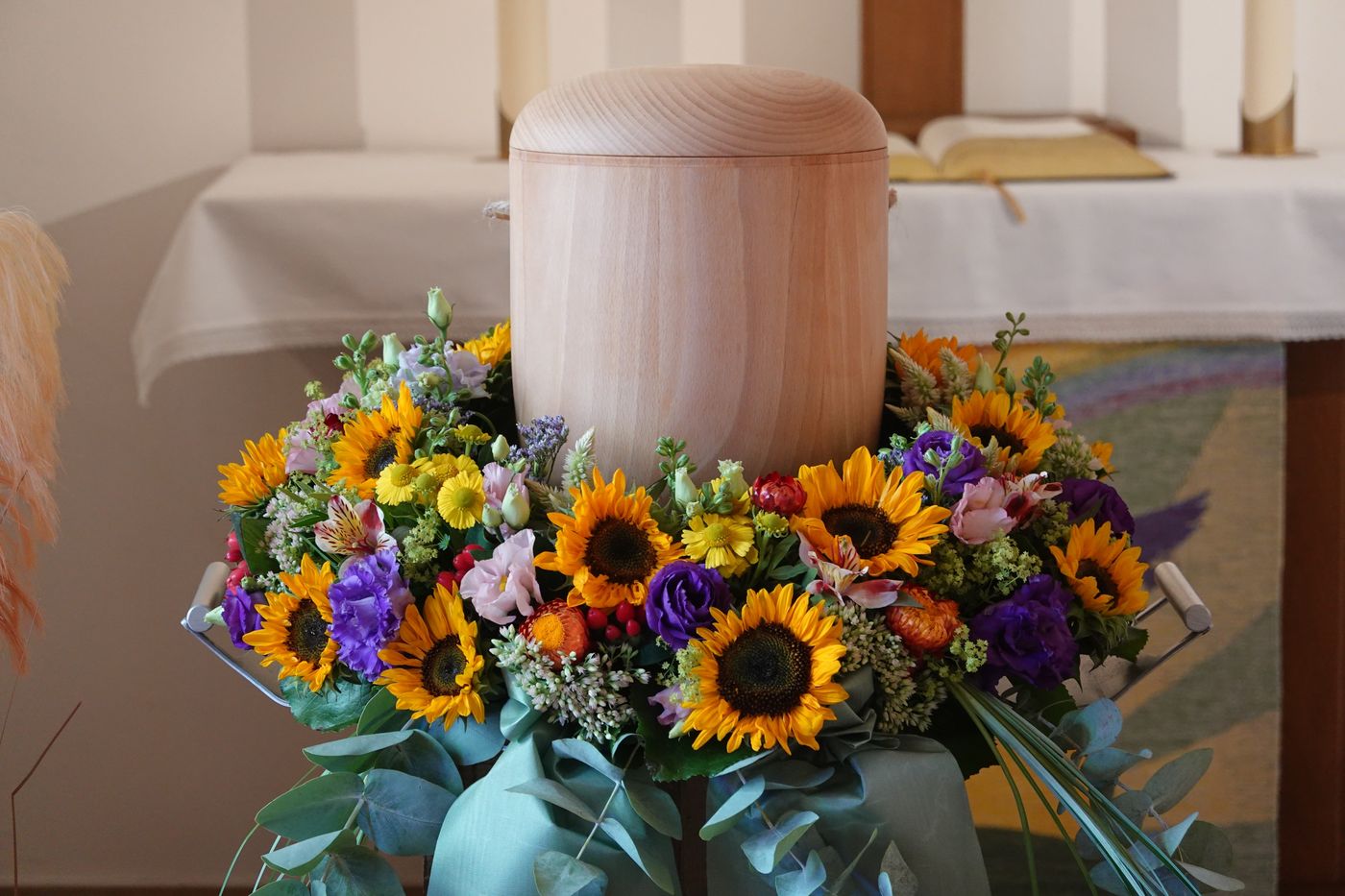 Urne mit Sonnenblumenkranz – Baumbestattung BaumFrieden
