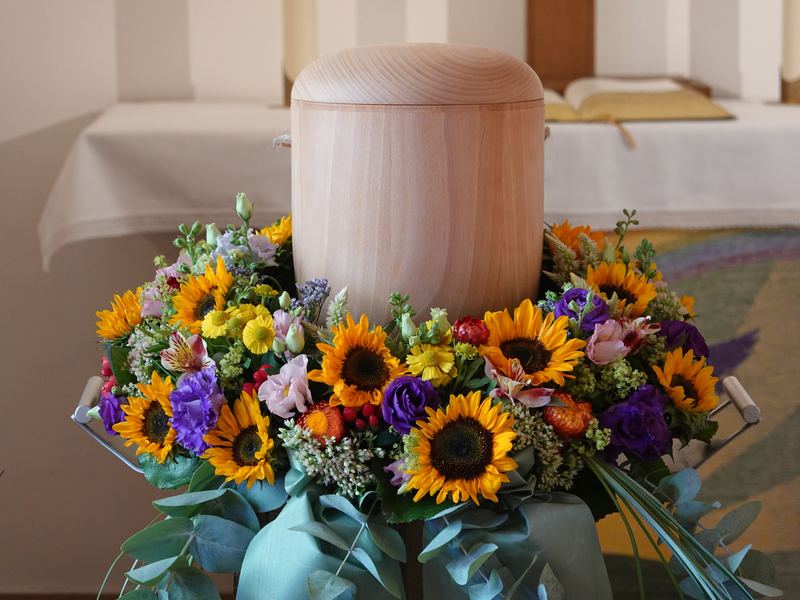 Helle Holzurne auf einem Kranz mit Sonnenblumen