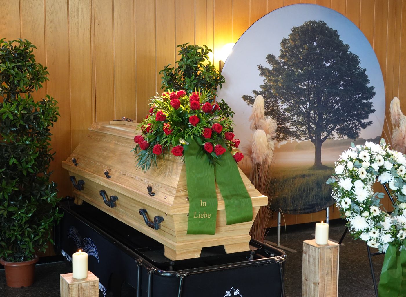 Sarg mit Blumenschmuck vor Baummotiv in der Trauerhalle
